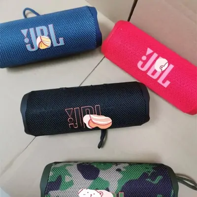 Two JBL portable Bluetooth speakers, one blue and one pink, beside a camouflage carrying case